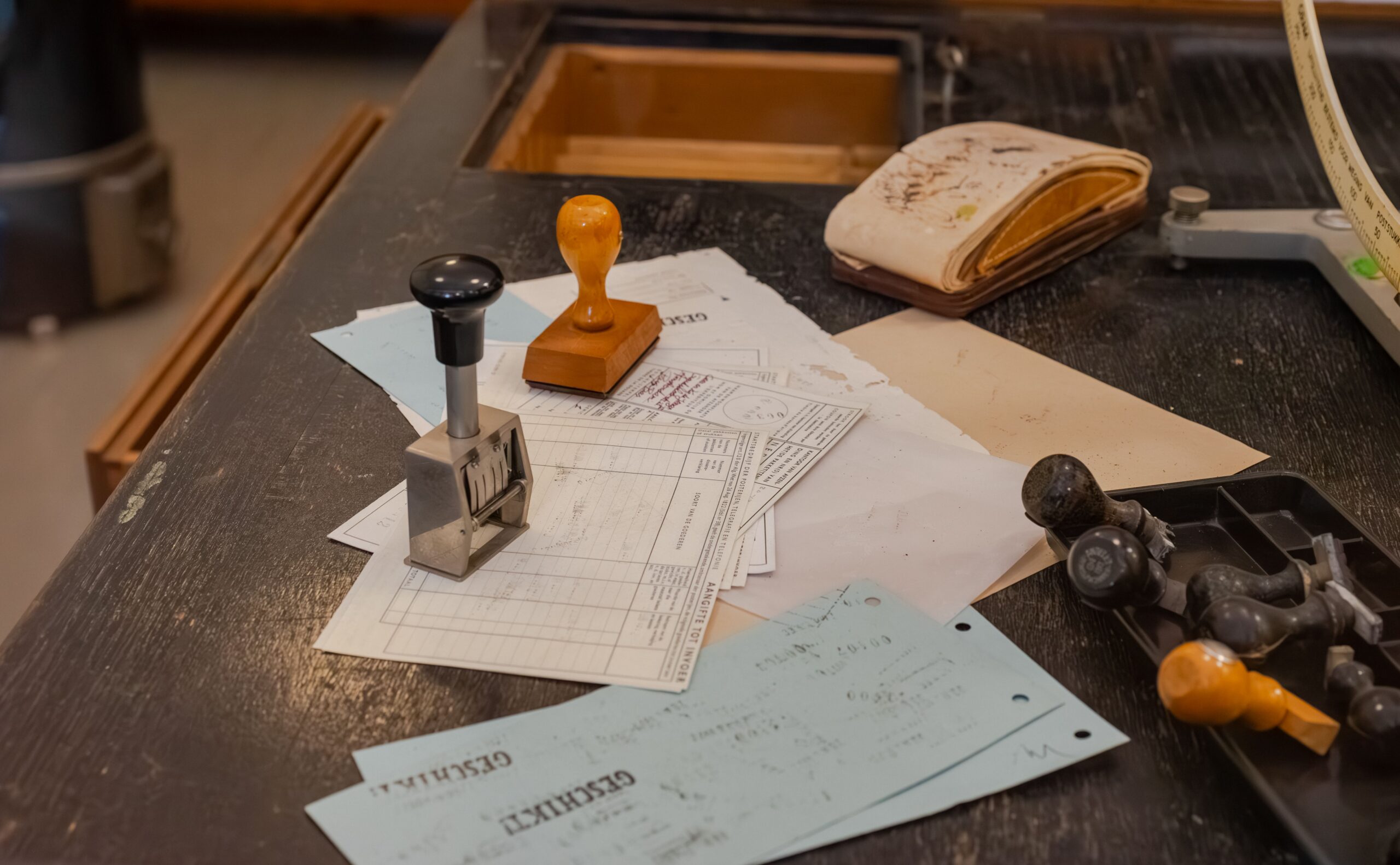 Cluttered desk with office stamps on top of various documents in an office setting.