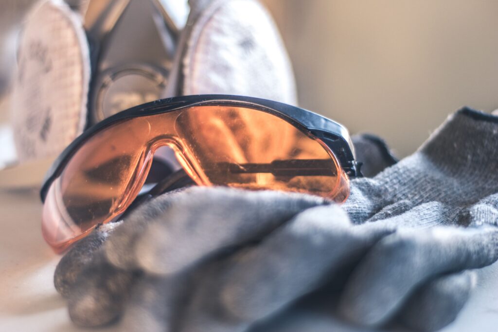 Close-up of safety glasses and gloves with a respirator, highlighting protective equipment.