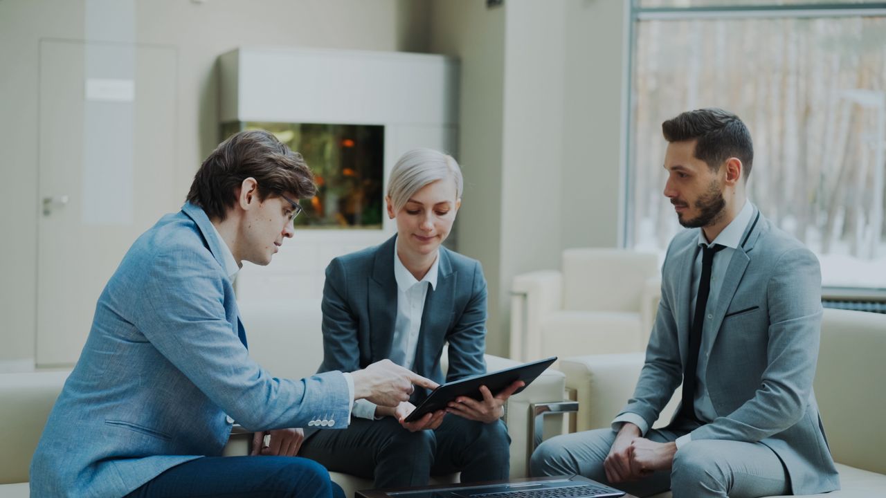 Three professionals engaging in a business meeting in a modern office setting.