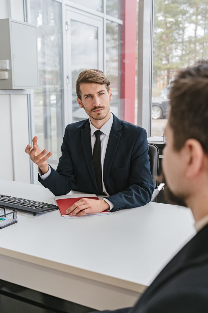 Businessman in a suit consulting a client in a modern office.